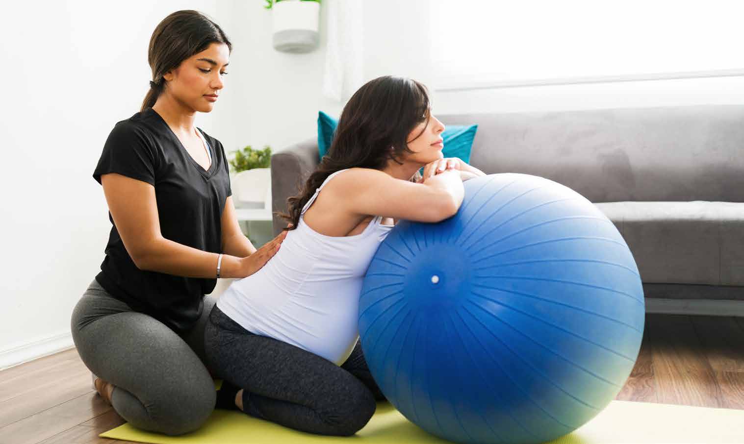 Pregnant mother receiving support from a Healthy Start doula during a birth ball exercise