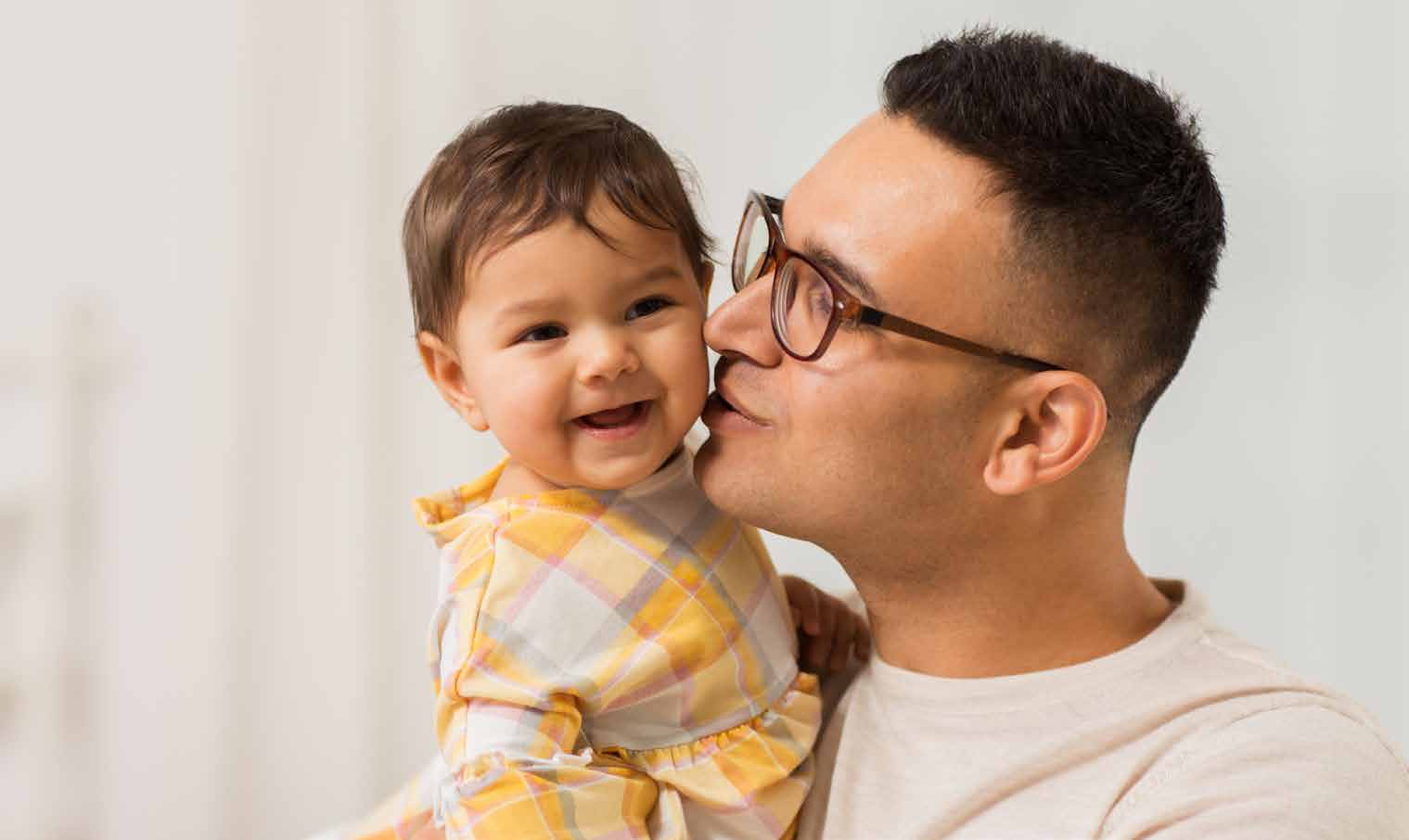Father holding and kissing his smiling young child