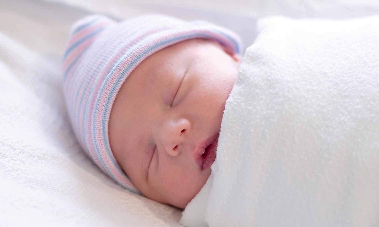 Sleeping newborn baby wrapped in a white blanket